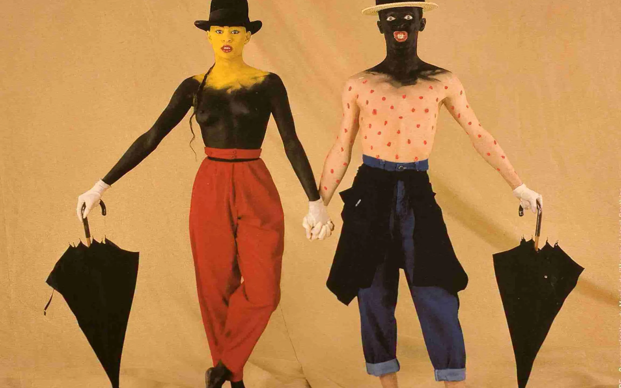 Un homme et une femme maquillés, torse nu avec des parapluies.