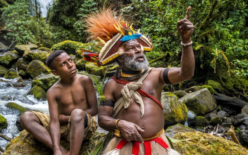 Le chef papou Mundiya Kepanga pointe le doigt vers le ciel montrant quelque chose à un jeune garçon