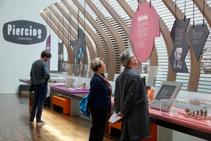 Visiteur dans l'expostion Piercing, devant une vitrine intitulée "Explosion".